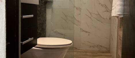 A bathroom with a toilet, a shower, and a sink.