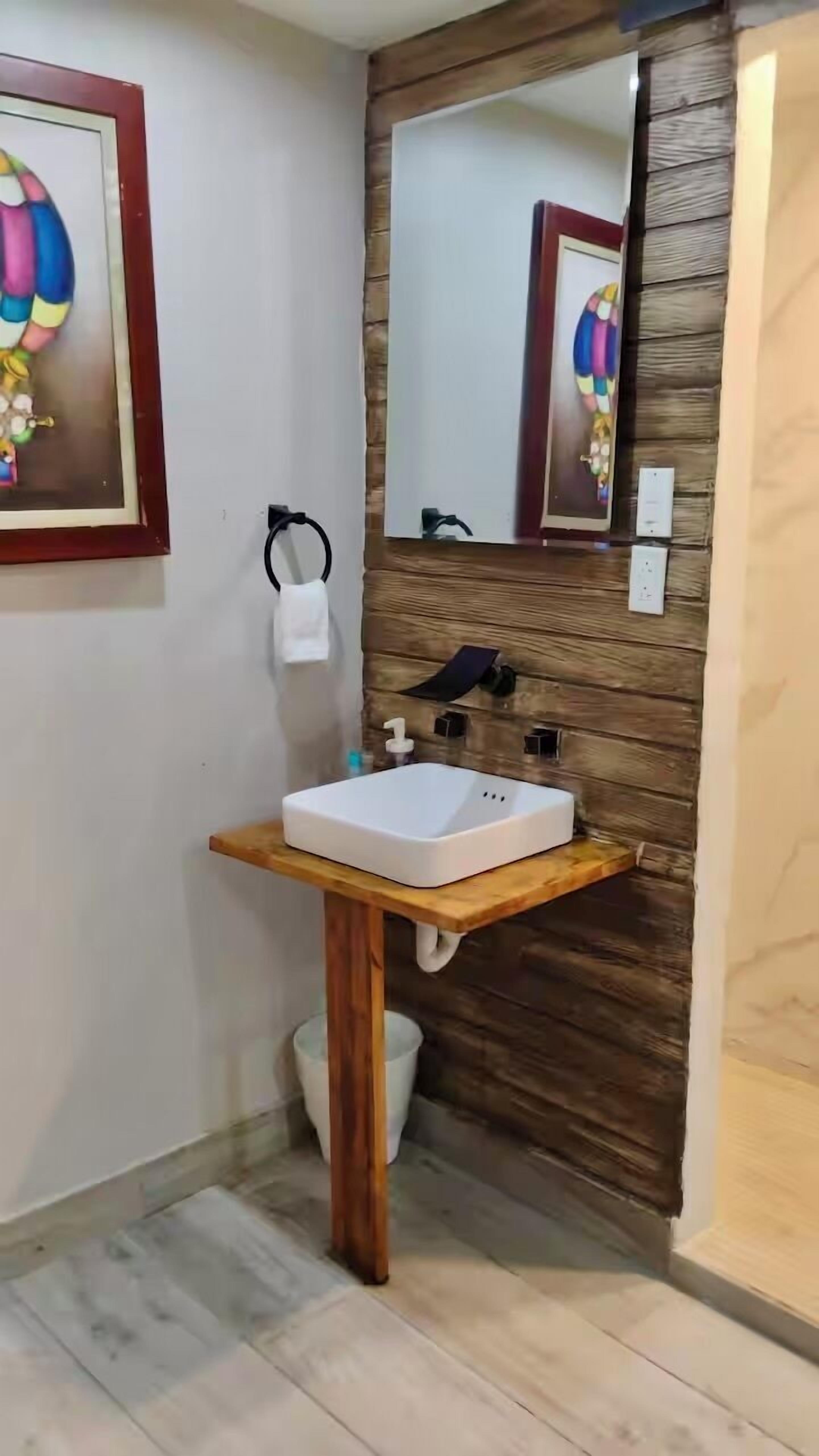 A bathroom with a wooden wall, a white sink, and a mirror.