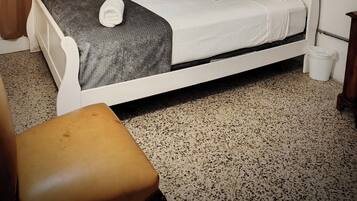 A bedroom with a bed, a chair, a wall-mounted air conditioner, and a map of the United States on the wall.