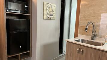 A modern kitchen with a built-in microwave, a stainless steel sink, and a wooden cabinet.