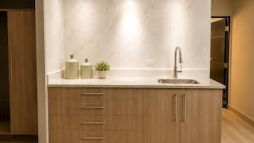 A modern kitchen with a marble backsplash, a stainless steel sink, and wooden cabinetry.