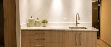A modern kitchen with a marble backsplash, a stainless steel sink, and wooden cabinetry.