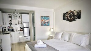 A hotel room with a bed, a desk, a chair, a sink, and a microwave. - Segovia Studio Units (Carolina)
