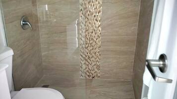 Un bagno con doccia, toilette e schienale rivestito di piastrelle decorate.
