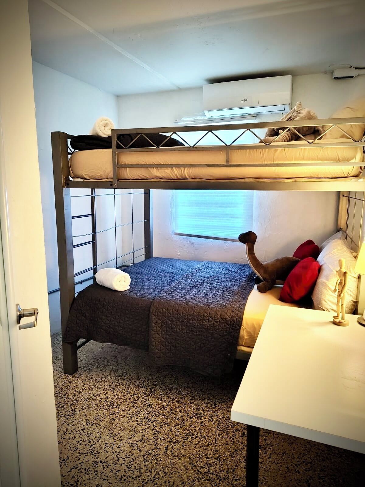 A bunk bed room with a window, a desk, and a chair.