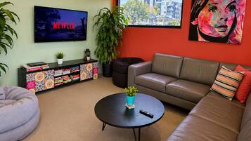 Una sala de estar moderna con un sofá, una mesa de centro, un sillón de mimbre, un televisor y una estantería.