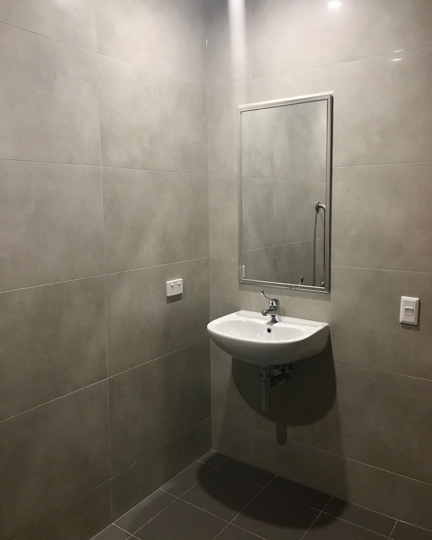 A bathroom with a white sink, a mirror, and tiled walls.
