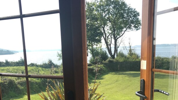 A wooden door with a view of a well-maintained lawn and a large tree. - Lakeside Cottage In Kesh with panoramic views over Lough Erne,  (Kesh, Fermanagh)