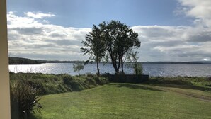 A grassy lawn with a tree and a view of a lake. - Lakeside Cottage In Kesh with panoramic views over Lough Erne,  (Kesh, Fermanagh)