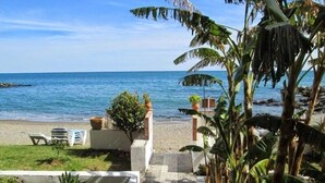 A pathway leading to a beach with lounge chairs and potted plants. - Apartment on the semi-private beach, terrace with sea views and WIFI (Benalmádena)