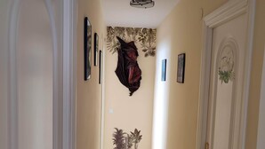 A hallway with a tiled floor, a wall-mounted sculpture, and several potted plants. - Apartment on the semi-private beach, terrace with sea views and WIFI (Benalmádena)