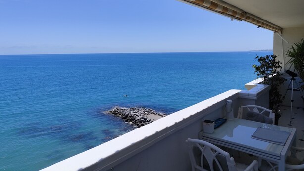 A balcony with a view of the sea, a table, chairs, and a potted plant. - Apartment on the semi-private beach, terrace with sea views and WIFI (Benalmádena)
