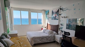 A bedroom with a bed, a desk, a chair, a TV, and a view of the sea. - Apartment on the semi-private beach, terrace with sea views and WIFI (Benalmádena)