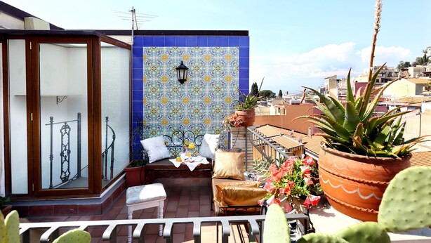 Un balcon avec un mur recouvert de carreaux, une plante en pot et un banc.