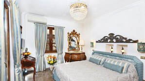 Une chambre à coucher avec un grand lit, une commode en bois, un miroir et un lustre.