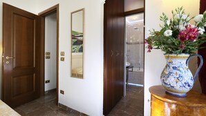 Un couloir avec une porte en bois, un miroir et un vase de fleurs posé sur une table en bois.