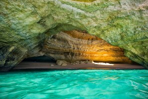 Formación natural de cueva con una piscina turquesa cristalina en el fondo.