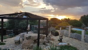 Un espace extérieur rustique agrémenté d’un chemin de pierre, d’une pergola en bois et d’une piscine.