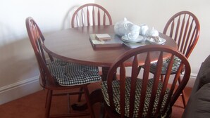 A dining table with four chairs, each with a checkered cushion. A teapot, cups, and saucers are placed on the table. - Superb sea views and  great location (Looe)
