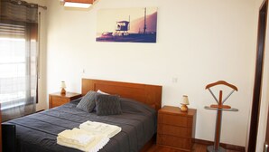 A bedroom with a bed, nightstands, a lamp, and a painting on the wall.