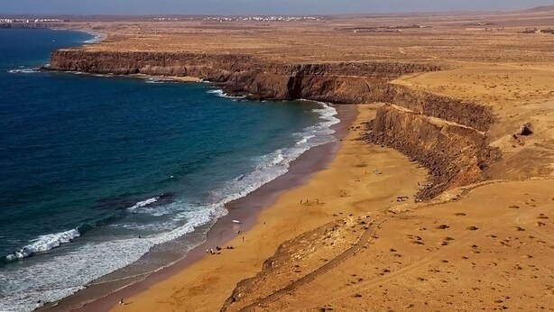 A coastal landscape with a sandy beach, cliffs, and a clear view of the ocean. - Spacious villa in Lajares with separate relaxation area and garden. (Lajares)