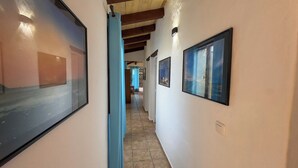 A hallway with framed artwork on the walls, a wooden ceiling, and a tiled floor. - Spacious villa in Lajares with separate relaxation area and garden. (Lajares)