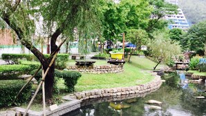 Un jardin paisible avec un étang, des bordures en pierre et une baignoire jaune.