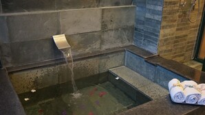 Une baignoire en pierre avec un robinet, de l’eau qui coule et un porte-serviettes avec des serviettes.