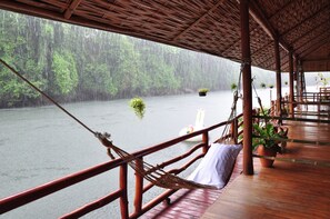 A wooden deck with a hammock and potted plants, overlooking a river. - Mek Kiri River Kwai Resort (Thong Pha Phum)
