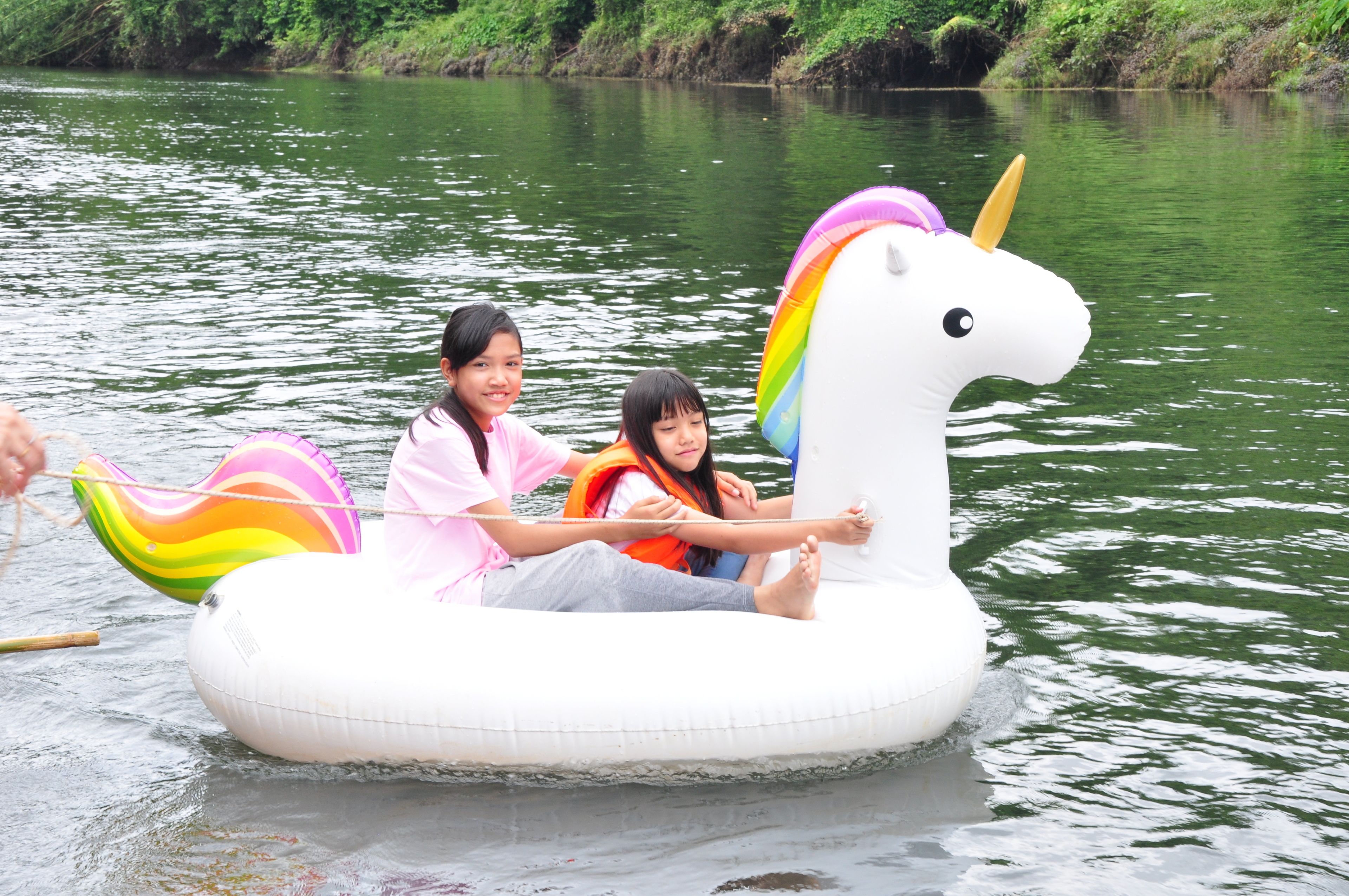 Dos personas en un flotador de unicornio blanco en un río.