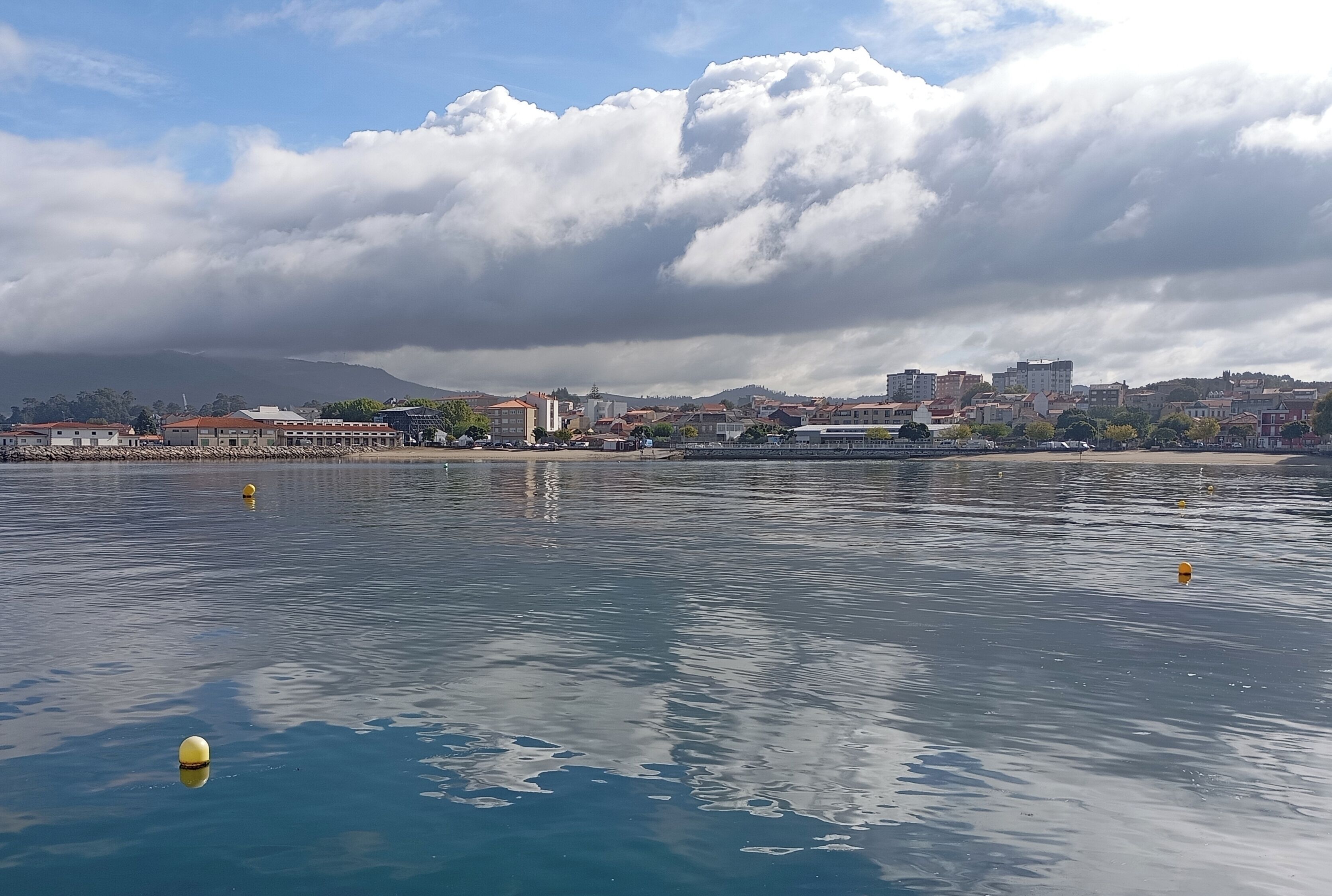 Un paisaje urbano costero con edificios, una playa y una masa de agua.