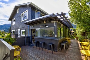 A modern house with a deck, outdoor seating, and a pergola. - The Black Sheep Backpackers (Queenstown)