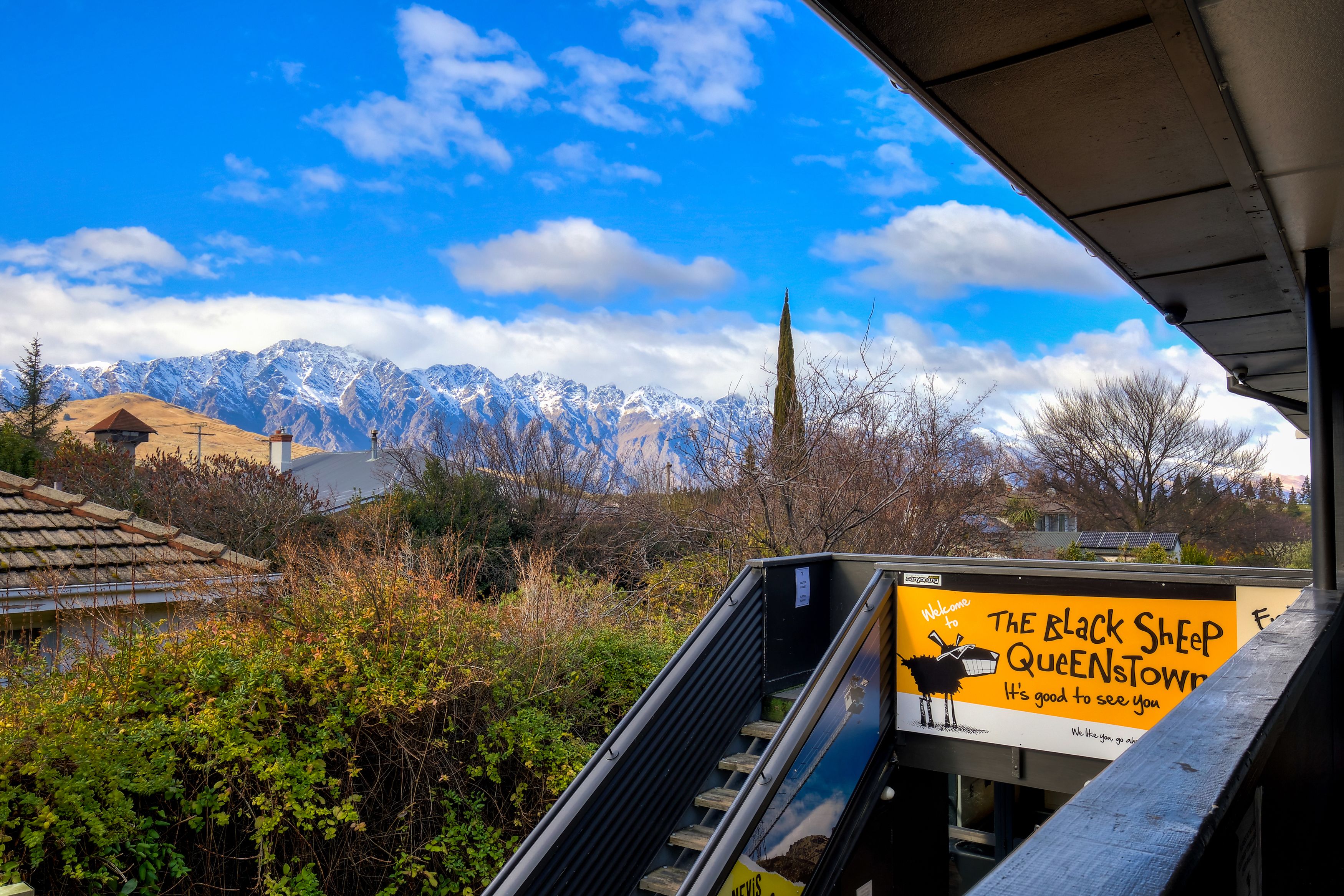 A view of mountains and a signboard for The Black Sheep Queenstown.