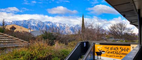 A view of mountains and a signboard for The Black Sheep Queenstown.
