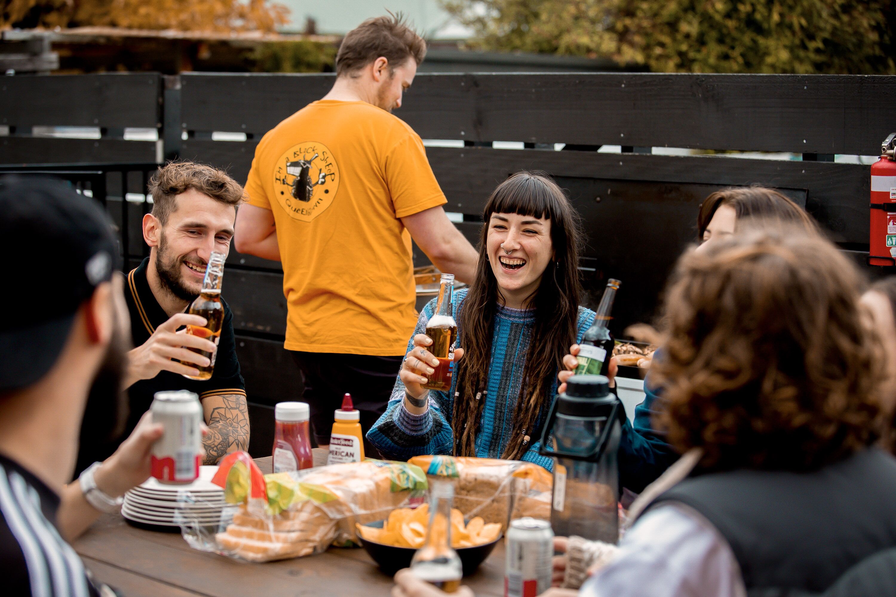 Un grupo de personas en un evento al aire libre con una mesa lista para comida y bebidas.