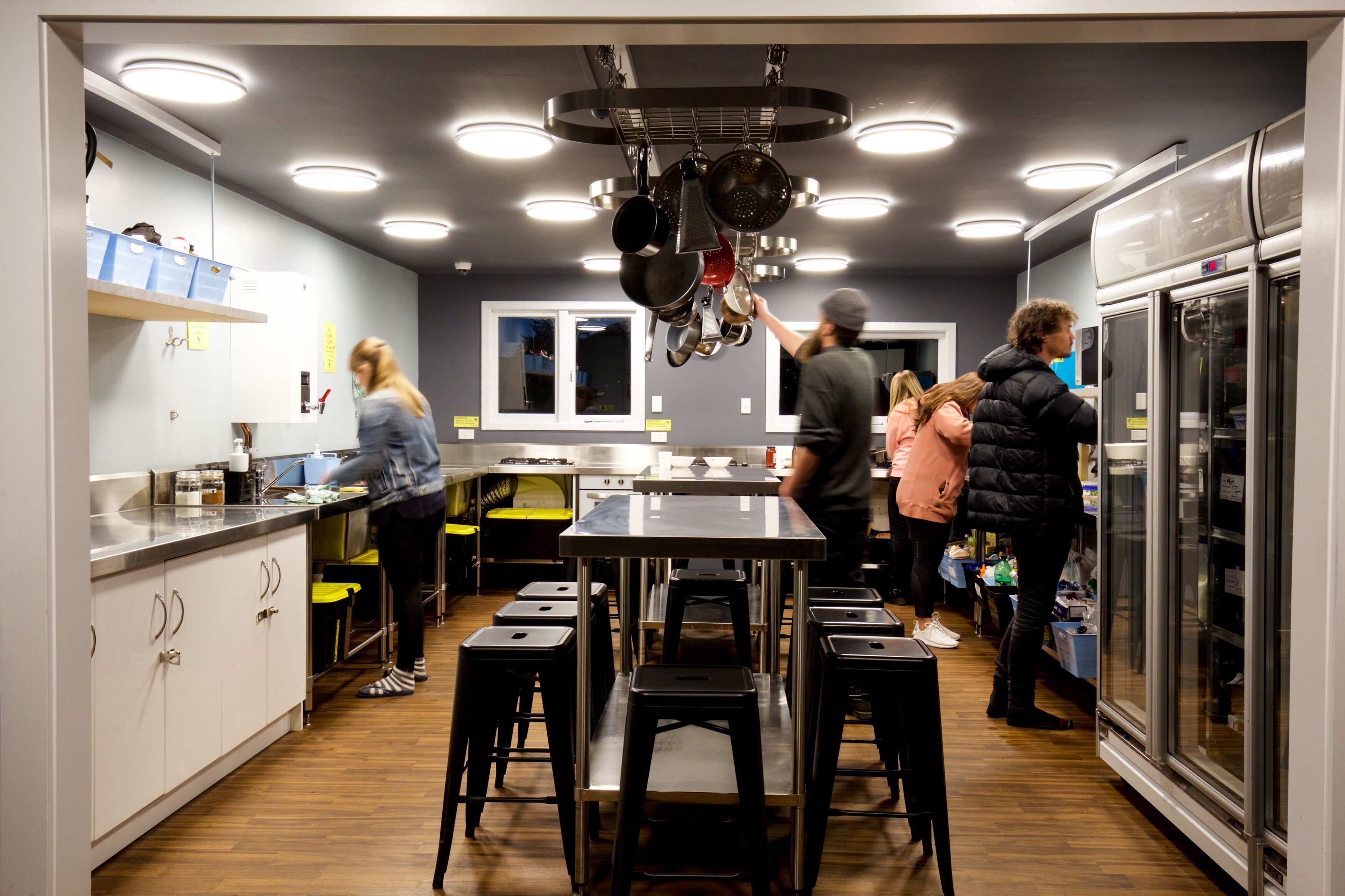 Una cocina moderna con una isla central, electrodomésticos de acero inoxidable y un colgador para ollas.