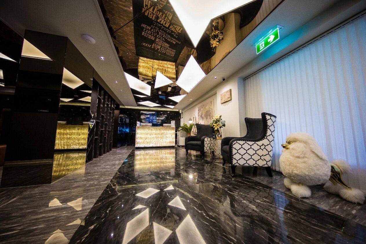 A hotel lobby with a reception desk, seating area, and a decorative ceiling.