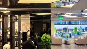 A modern lobby with a seating area, a large digital display, and a potted plant. - Sora Hotel Silom (Bangkok)