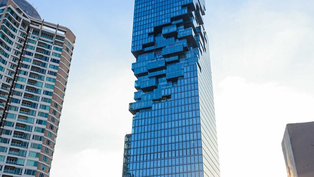 A tall, modern skyscraper with a unique, reflective glass facade.