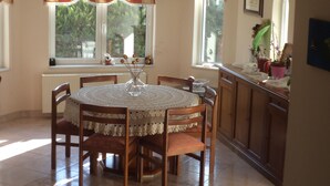 A dining area with a round table, chairs, a radiator, and a window with curtains.