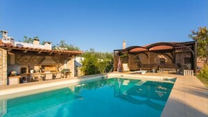 A swimming pool with a pergola and outdoor seating area.