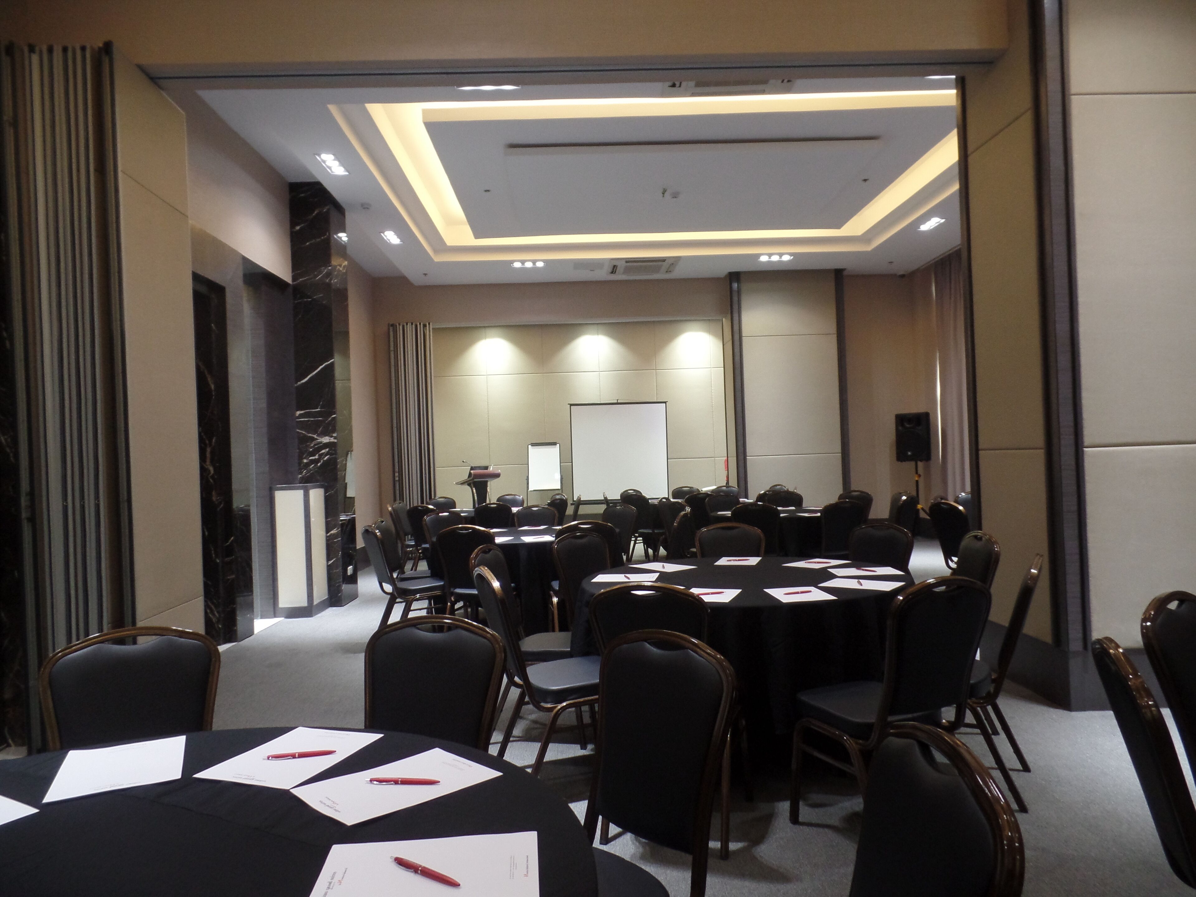 A conference room with a whiteboard, projector, and multiple tables with chairs.
