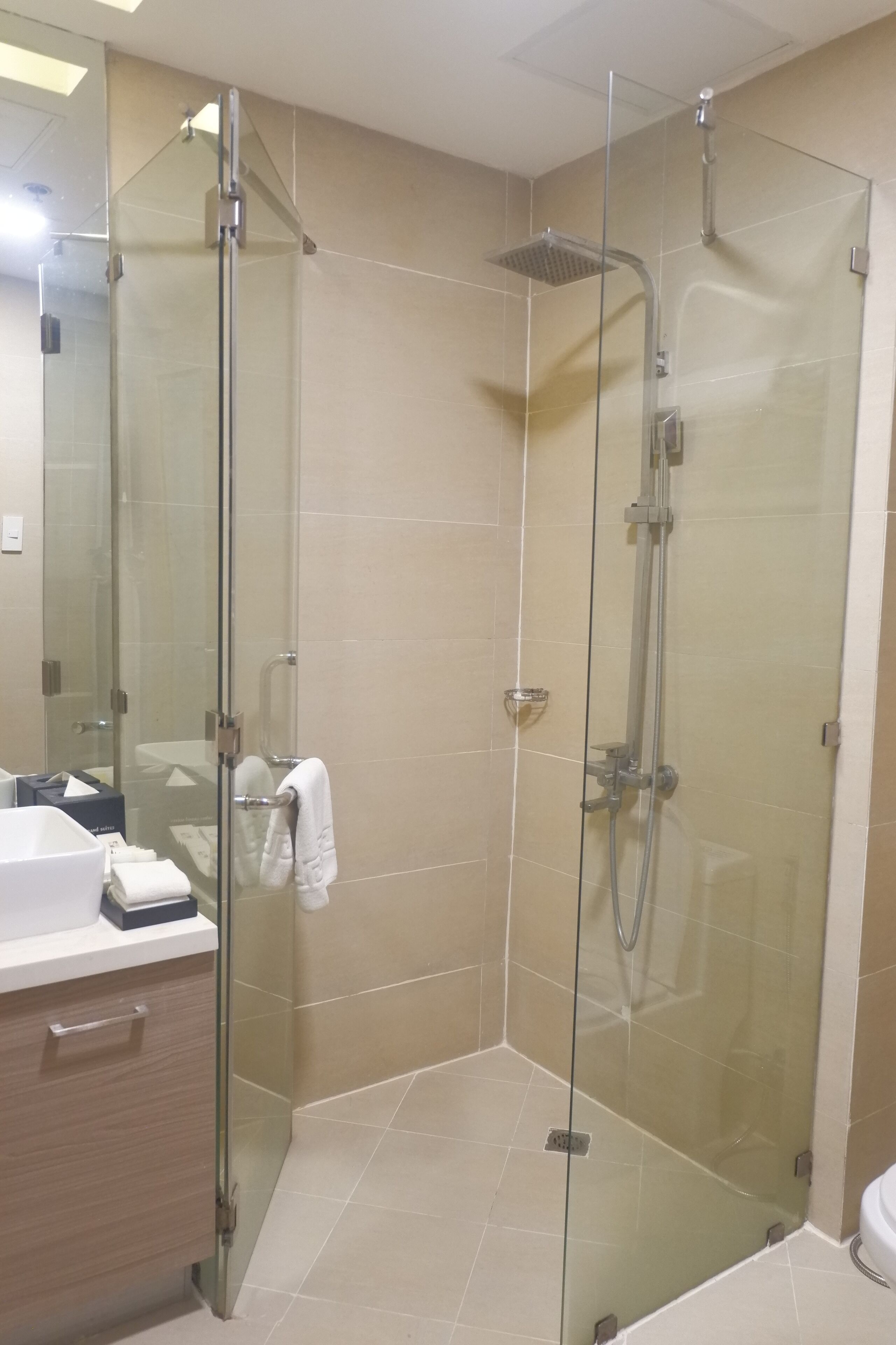 Un baño moderno con ducha de vidrio, lavamanos blanco y espejo.
