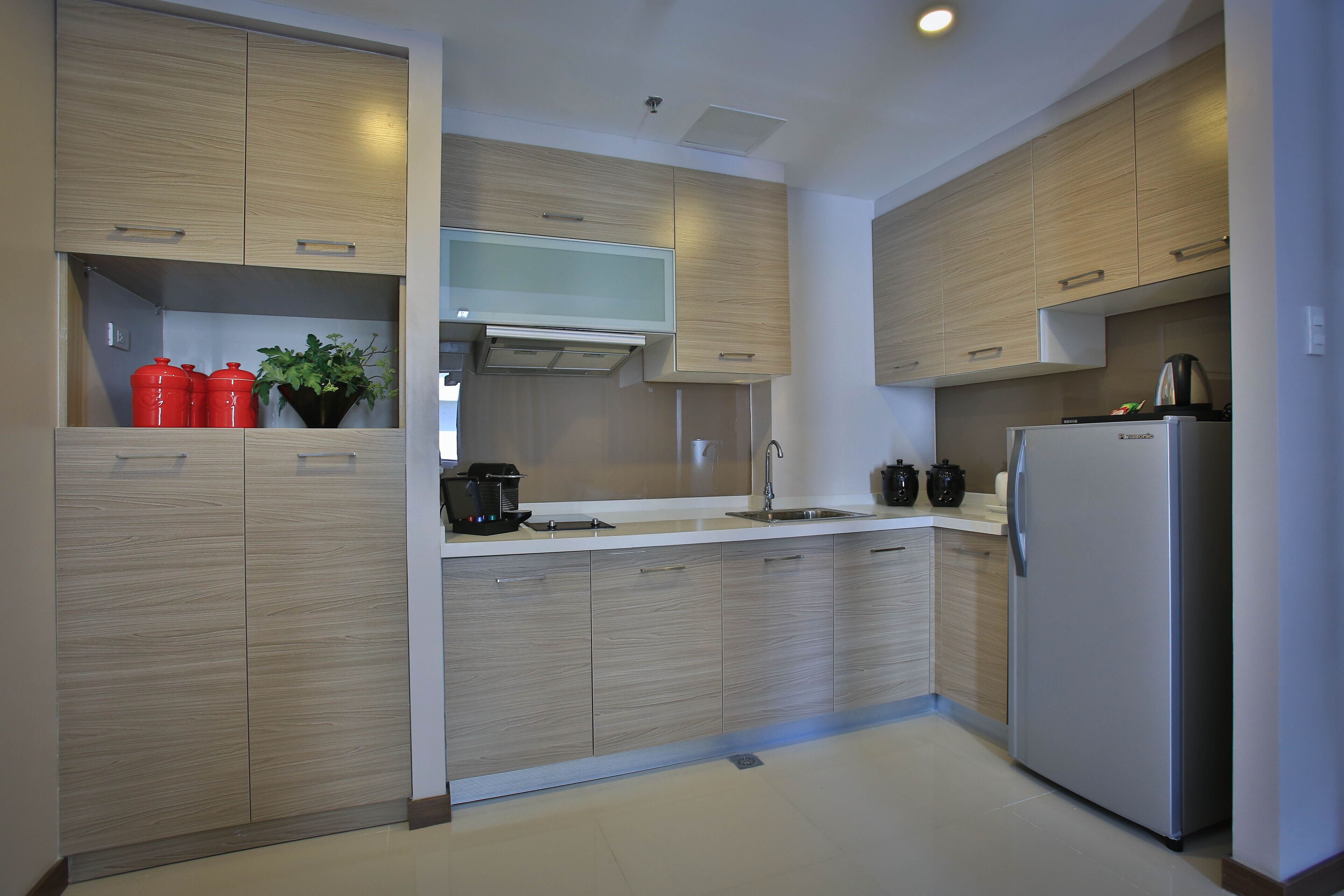 Una cocina moderna con armarios de madera, un refrigerador de acero inoxidable y una cafetera.