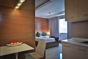 Ein Hotelzimmer mit Bett, Nachttisch, Sessel und einem Tisch mit Obstschale.