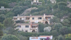 A hillside villa with multiple buildings, surrounded by lush greenery and trees.