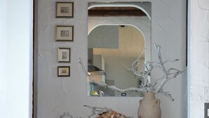 A hallway with a wooden console table, a mirror, and a vase with branches.