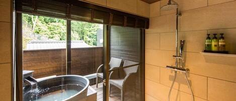 A modern bathroom with a glass-enclosed hot tub, a shower, and a small shelf with toiletries.
