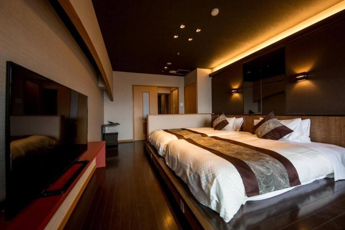 Ein modernes Hotelzimmer mit einem großen Bett, einem Fernseher und Holzboden.