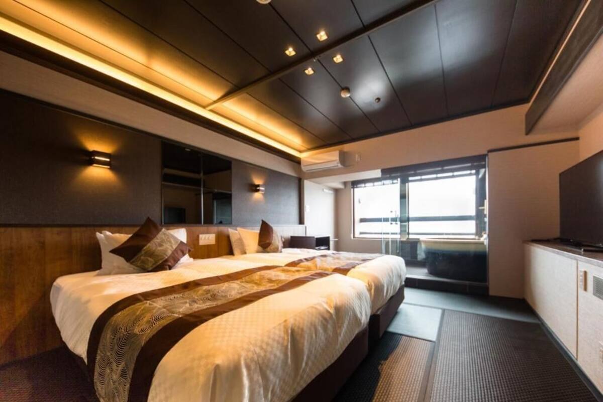 Ein modernes Hotelzimmer mit einem großen Bett, einem Flachbildfernseher und Blick ins Freie.